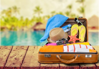 Retro suitcase with travel objects on wooden