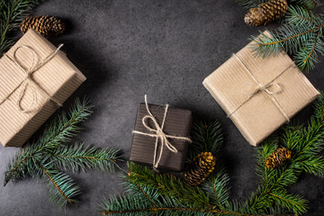 Fototapeta na wymiar Black and brown paper christmas gift box with pine branches on dark texture surface.
