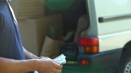 Man counting banknotes and closing van door, small business, moving company