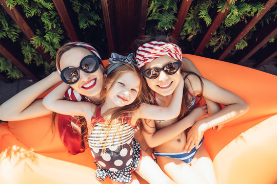 Beautiful mother with two daughters sitting on an orange lounge