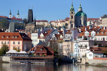 Fototapeta premium Colorful autumn Prague St. Nicholas' Cathedral with the Lesser Town above River Vltava in the sunny Day, Czech Republic
