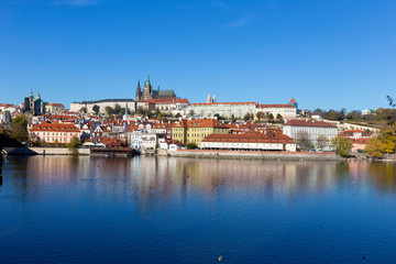 Colorful autumn Prague gothic Castle with the Lesser Town above River Vltava in the sunny Day,...