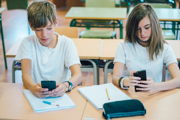 Fototapeta premium Couple young students with smartphone at school