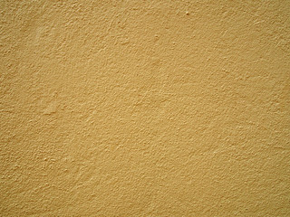 a pale yellow concrete grainy textured wall painted a bright light yellow color