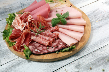Food tray with delicious salami, pieces of sliced ham, sausage and salad. Meat platter with selection.