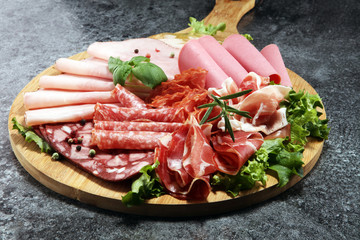 Food tray with delicious salami, pieces of sliced ham, sausage and salad. Meat platter with selection.