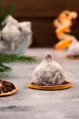 Chocolate candy in powdered sugar, stacked on a slice of dried lemon.