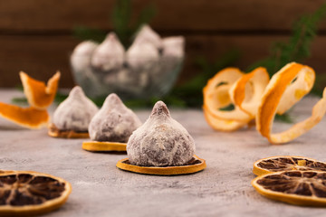Chocolate candies with slices of dry lemon on a wooden background, decoration of the holiday table.