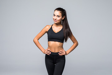 Portrait of sexy young woman with her hands on hips looking at camera. Fitness female with muscular body ready wearing hand gloves for workout on grey background