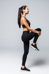 Fitness woman doing stretching legs workout. Full length shot of young woman on white background. Stretching and motivation