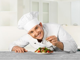 Portrait of a male chef cook preparing salad  isolated on