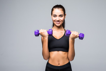Sporty woman does the exercises with dumbbells on white background. Muscular woman in sportswear on white background. Strength and motivation.