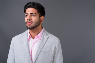 Young handsome Indian businessman against gray background