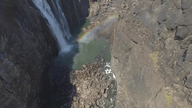 View from above of a rainbow and a waterfall inside the canyon at Victoria Falls during Dry Season