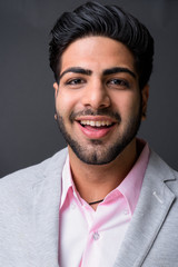 Obraz premium Young handsome Indian businessman against gray background