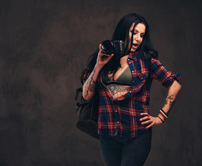 Seductive tattooed hipster girl wearing a red unbuttoned checked shirt posing a camera.