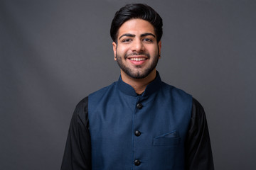 Obraz premium Young handsome Indian businessman against gray background