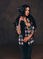 Fototapeta na wymiar Seductive tattooed girl wearing an unbuttoned checked shirt girl posing with a camera.