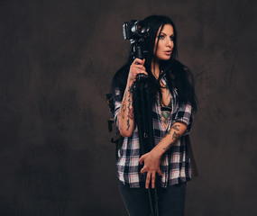 Seductive tattooed girl wearing an unbuttoned checked shirt girl posing with a camera.