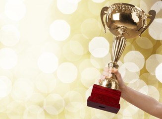 Hand of kid holding champion cup on glossy background
