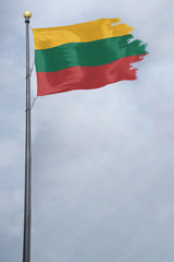 Fototapeta na wymiar Worn and tattered Lithuania flag blowing in the wind on a cloudy day