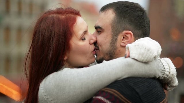 Young Happy Attractive Amorous Couple Embracing And Kissing Outdoor. Merry Christmas and New Year Concept. Good Mood and Having Fun Together.