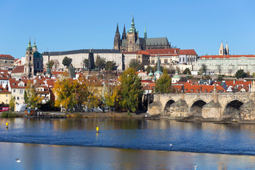 Colorful autumn Prague gothic Castle and Charles Bridge with the Lesser Town in the sunny Day,...
