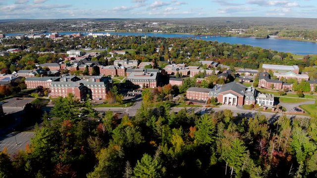 AERIAL: View of university campus with city and river in the background on sunny day