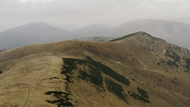 Ascending aerial shot of dry peak covered with little greenery, Slovakia