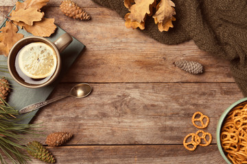 Flat lay composition with hot cozy drink and autumn leaves on wooden background. Space for text