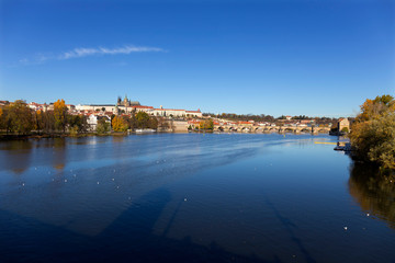 Naklejka na ściany i meble Colorful autumn Prague gothic Castle and Charles Bridge with the Lesser Town in the sunny Day, Czech Republic