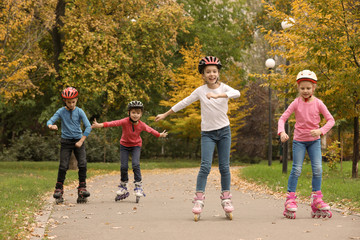 Fototapeta premium Happy children roller skating in autumn park