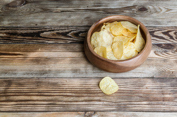 Chips in a bowl. A snack for beer on a wooden table.