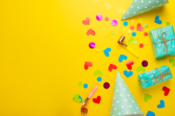 Birthday caps, blowers and confetti on a bright background