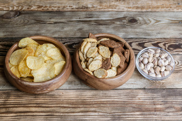 Snacks for beer on a wooden table. Chips, croutons, bread sticks and pistachios