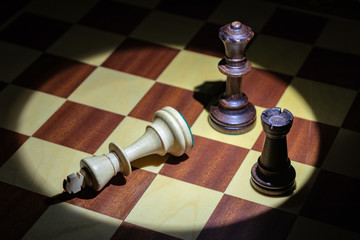 background. chess pieces (white, black) stand on a chessboard