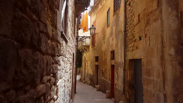 Narrow old alley with with balconies and hanged clothes on it. Video made in the city of Modica, Sicily, Italy.