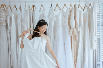 Asian young woman bride trying on wedding dress at modern wedding