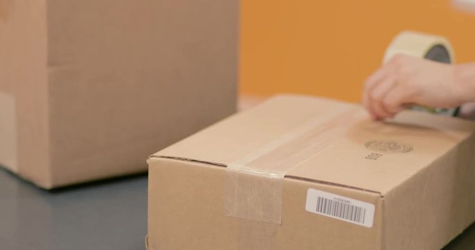 Taping and sealing a package box for shippment. Save money this Holiday using recycled boxes. Shot in 4k 30fps