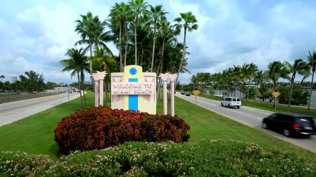 Shot of sign that reads Welcome to Miami Beach in Miami with cars passing by