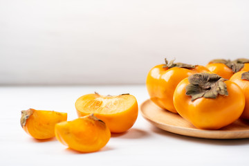 Fototapeta na wymiar Half and sliced persimmon fruit on white table, healthy fruit