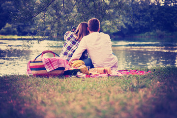 Couple taking a selfie by mobile phone while enjoying picnic time