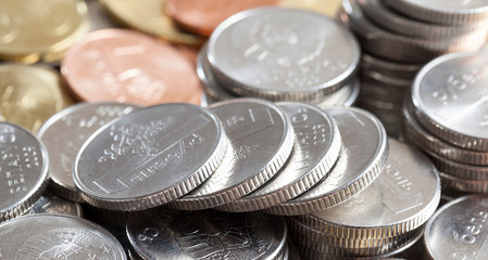 silver color of Belarus coins, stacked in a pile, in the background another color of coins