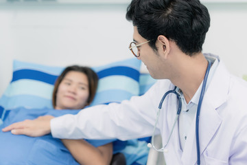 Asian young pregnant woman lying down talking and visit to her doctor man in a room.