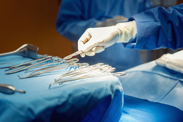 Detail shot of steralized surgery instruments with a hand grabbing a tool