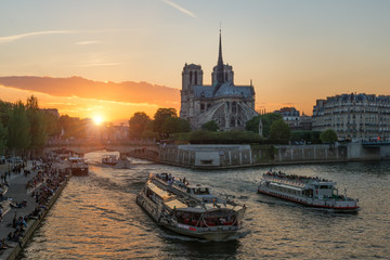 Notre Dame de Paris cathedral with cruise ship in Seine river in Paris, France. Beautiful sunset in...