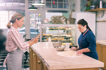 Filming chef. Blonde-haired owner of bakery filming her chef cooking croissants for online course