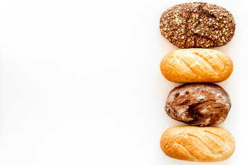 Loafs of white and brown homemade bread on white background top view copy space