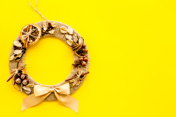 Creative, unusual christmas wreath made of thread, dry fruits and nuts on yellow background top view copy space