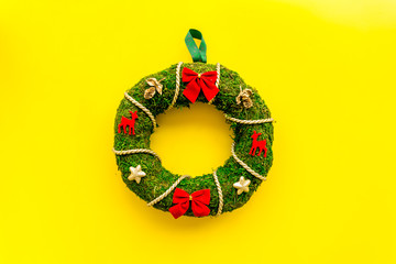 Christmas wreath traditional, classic type. Wreath made of spruce branches and red ribbons on yellow background top view copy space